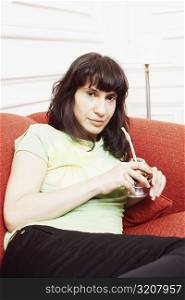 Portrait of a mid adult woman reclining on a couch and holding a glass