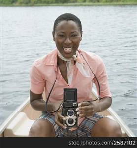 Portrait of a mid adult woman sitting on a boat and holding a twin lens camera