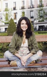 Portrait of a mid adult woman sitting on a park bench and smiling