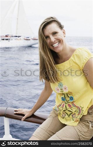 Portrait of a mid adult woman sitting on a railing and smiling