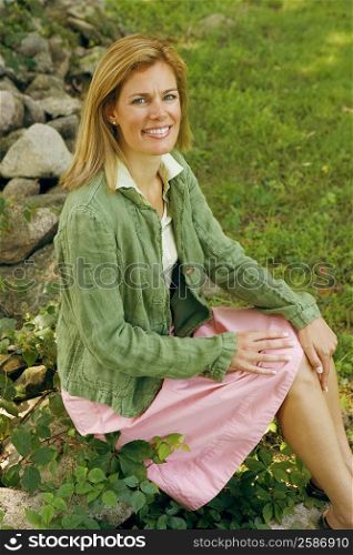 Portrait of a mid adult woman sitting on a rock and smiling