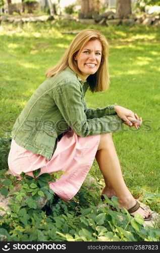 Portrait of a mid adult woman sitting on a rock and smiling