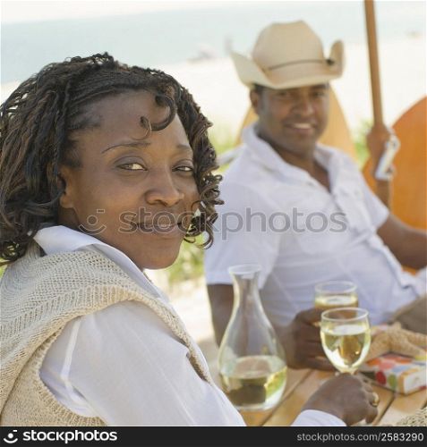 Portrait of a mid adult woman sitting on the beach with a mature man and smiling