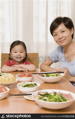 Portrait of a mid adult woman sitting with her daughter at a dining table