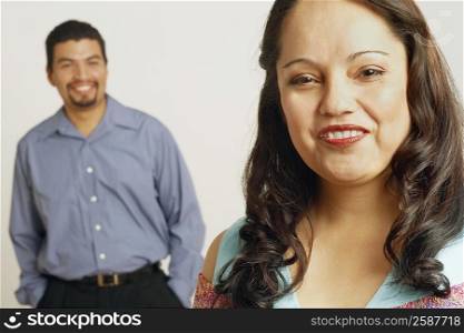 Portrait of a mid adult woman smiling with a mid adult man standing in the background