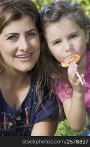 Portrait of a mid adult woman smiling with her daughter eating a candy