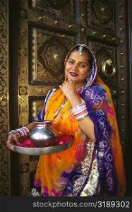 Portrait of a mid adult woman standing in front of a door and greeting, Jaipur, Rajasthan, India