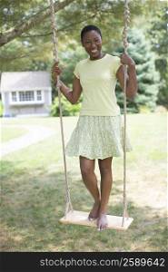 Portrait of a mid adult woman standing on a rope swing and smiling