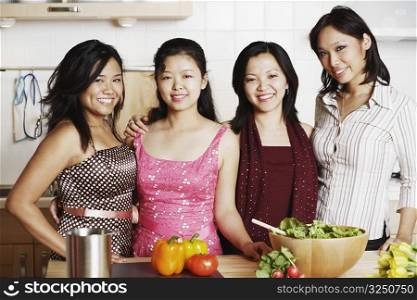 Portrait of a mid adult woman standing with three young women in the kitchen