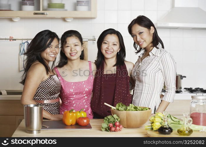 Portrait of a mid adult woman standing with three young women in the kitchen