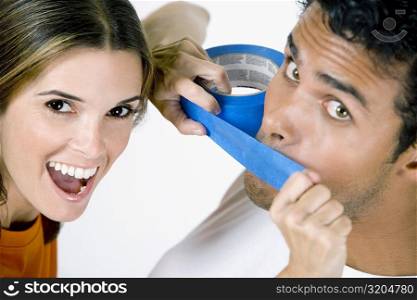 Portrait of a mid adult woman sticking an adhesive tape on a young man&acute;s mouth