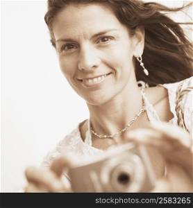 Portrait of a mid adult woman taking a picture with a digital camera
