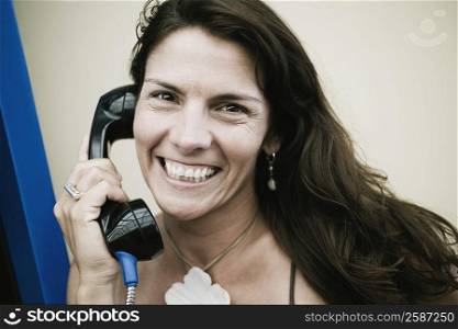 Portrait of a mid adult woman talking on a pay phone