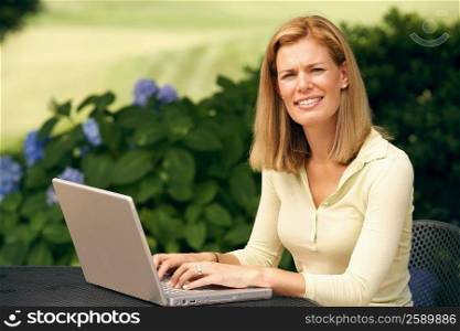 Portrait of a mid adult woman using a laptop in a park