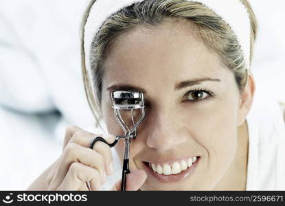 Portrait of a mid adult woman using an eyelash curler and smiling
