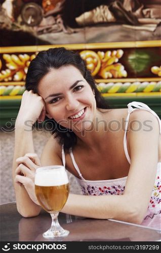 Portrait of a mid adult woman with a glass of beer in front of her