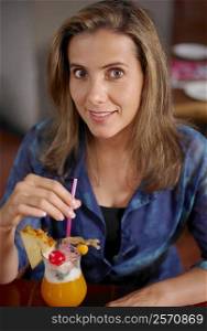 Portrait of a mid adult woman with a glass of pina colada in front of her
