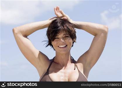 Portrait of a mid adult woman with her hands on her head and smiling