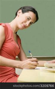 Portrait of a mid adult woman writing with a pen on a sheet of paper