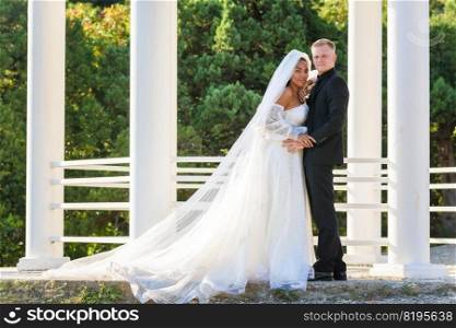 Portrait of a mixed race newlyweds in front of a gazebo with round columns