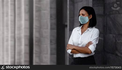 Portrait of a Mixed Races Business Woman, Wearing a Surgical Mask. Healthcare in New Normal Lifestyle Concept. Crossed Arm and Looking away
