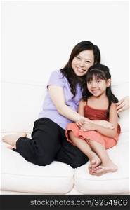 Portrait of a mother sitting on a couch with her daughter