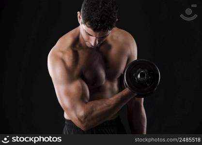Portrait of a muscular man lifting weights against a dark background