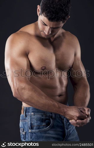 Portrait of a muscular man posing without a shirt against dark background