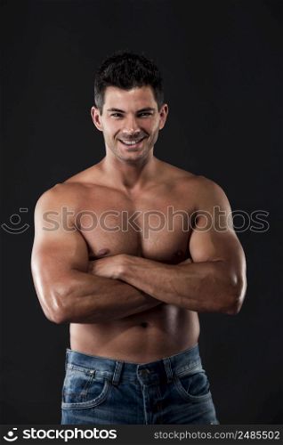 Portrait of a muscular man posing without a shirt against dark background