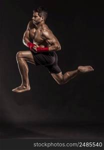 Portrait of a muscular man practicing body combat against a dark background