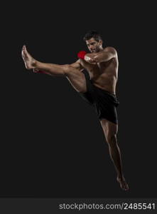 Portrait of a muscular man practicing body combat against a dark background