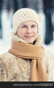 Portrait of a natural adult woman with a scarf and a a woolen hat, outdoor during winter