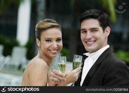 Portrait of a newlywed couple holding champagne flutes and smiling