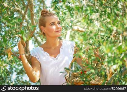 Portrait of a nice blond dreamy woman enjoying nature of a countryside, girl walking in the olive garden, harvesting time in autumn season