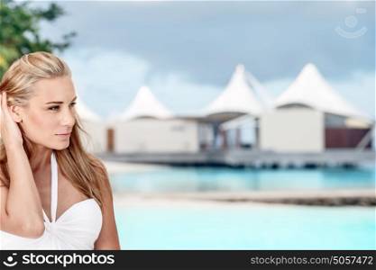 Portrait of a nice blond girl on the beach over luxury bungalow background, spending summer vacation near the ocean, Maldives