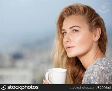Portrait of a nice calm blond female drinking tea on the outdoors terrace, having breakfast at home, feeling morning pleasure and relaxation