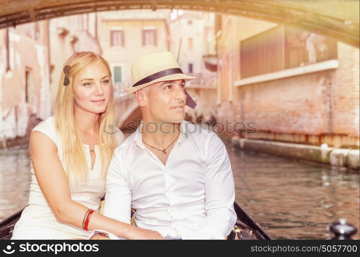 Portrait of a nice couple sitting in the gondola and enjoying wonderful trip along canal on narrow Venice street, romantic travel to Italy, Europe