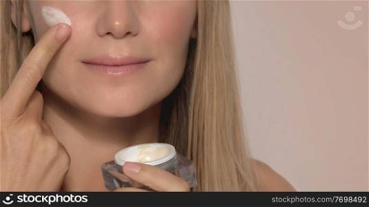 Portrait of a Nice Girl Applying Facial Moisturizer Cream Isolated on Beige Background. Face Part. Natural Cosmetics. Healthy Lifestyle. Beauty and Happiness Concept.. Beautiful Girl Applying Facial Cream