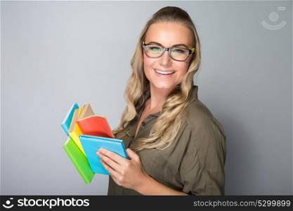 Portrait of a nice happy student girl wearing glasses reading book in the studio over gray background, gain knowledge in the college