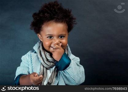 Portrait of a Nice Little African-American Boy Dressed in Stylish Clothes Posing over Dark Background in the Studio. Baby Model.