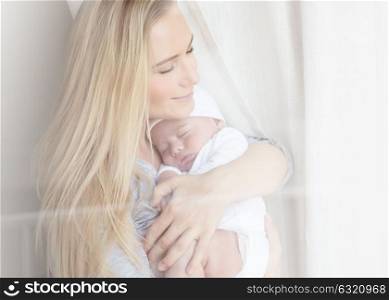 Portrait of a nice mother with closed eyes of pleasure holding adorable newborn sleeping baby, happy motherhood concept