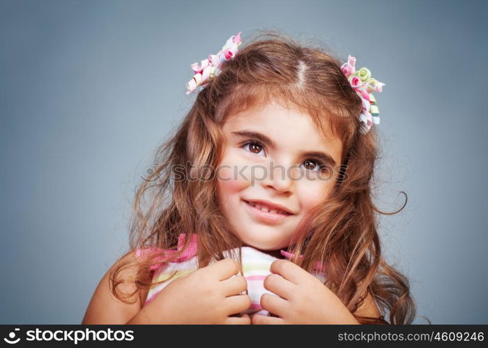 Portrait of a nice shy baby girl over gray background, precious little child, happy childhood
