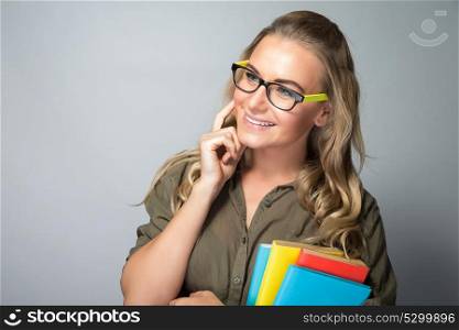Portrait of a nice student girl thinking, resolving task of an exam, education in a high school, shot over gray background