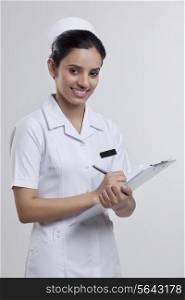 Portrait of a nurse writing on a clipboard