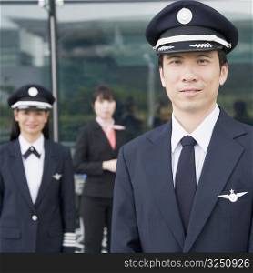 Portrait of a pilot with a female pilot and a cabin crew standing in the background