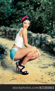 Portrait of a pin-up girl. American style, in a garden, wearing jeans and t-shirt