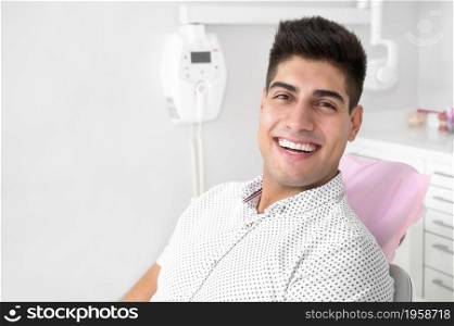 Portrait of a positive handsome patient smiling looking at camera, after treatment at dental clinic. High quality photo.. Portrait of a positive handsome patient smiling looking at camera, after treatment at dental clinic.