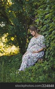 Portrait of a pregnant girl walking in the summer garden.. Expectant mother waiting for a miracle walks in the garden 1655.