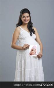 Portrait of a pregnant woman holding a picture of a baby