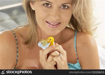 Portrait of a pregnant woman holding two pacifiers